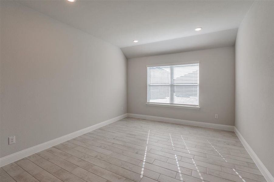 Versatile interior space featuring wood-finish flooring, neutral wall tones, recessed lighting, a window with blinds, and clean baseboards