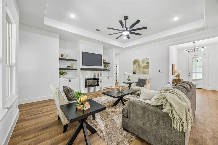 Spacious living area featuring wood-finish flooring, a contemporary ceiling fan, recessed lighting, and a tray ceiling