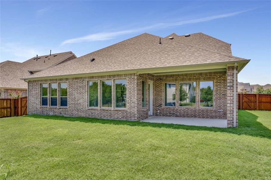 Back of property featuring a patio area and a lawn