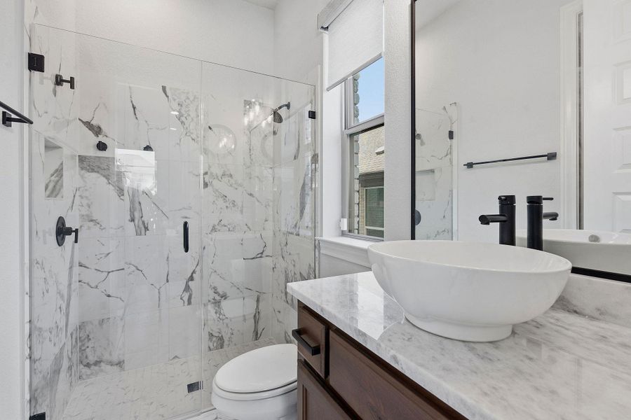 A modern bathroom features a sleek glass-enclosed shower with marbled walls and a stylish vessel sink atop a rich wooden vanity. A modern bathroom features a sleek glass-enclosed shower with marbled walls and a stylish vessel sink atop a rich wooden vanity.