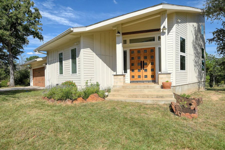 Entrance to property featuring covered porch, a lawn, and an attached garage Entrance to property featuring covered porch, a lawn, and an attached garage