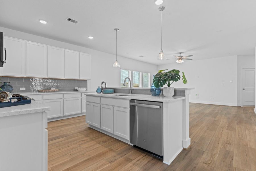 Stunning view of the kitchen from the opposite angle reveals the deep undermount sink, built-in dishwasher, and panoramic flow into the light-filled family room. **Image Representative of Plan Only and May Vary as Built**.