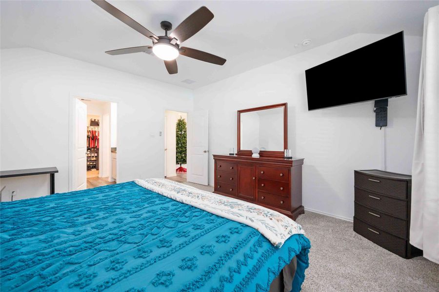 Spacious primary bedroom with room to unwind, showcasing plush carpet, ceiling fan, and a well-designed layout that flows seamlessly into the ensuite bath and walk-in closet—ideal for a private retreat at day’s end. Spacious primary bedroom with room to unwind, showcasing plush carpet, ceiling fan, and a well-designed layout that flows seamlessly into the ensuite bath and walk-in closet—ideal for a private retreat at day’s end.