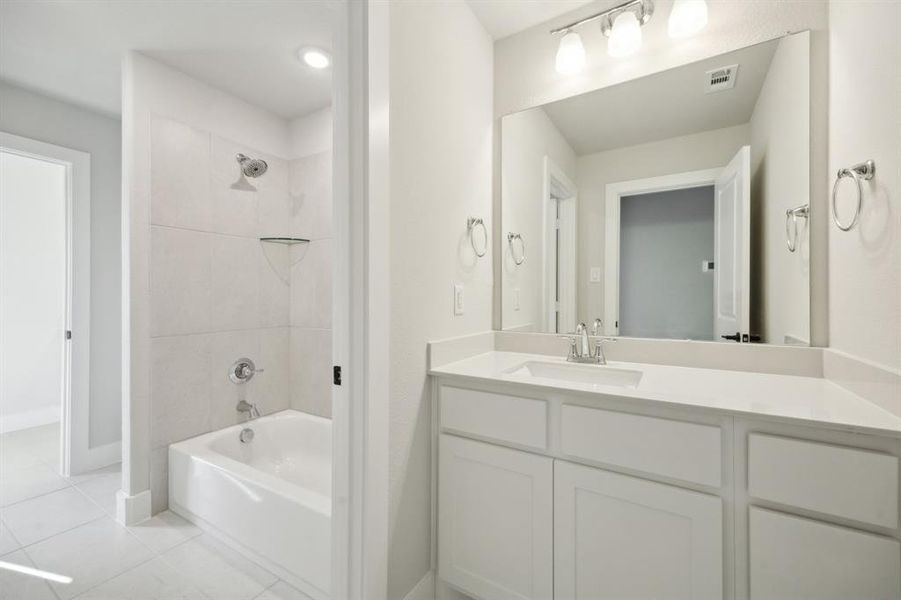 Bathroom with tile patterned flooring, vanity, and tiled shower / bath combo