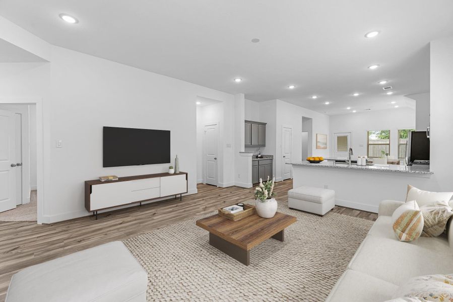 The family room is seamlessly connected to the open kitchen. Virtually staged to show furniture placement.