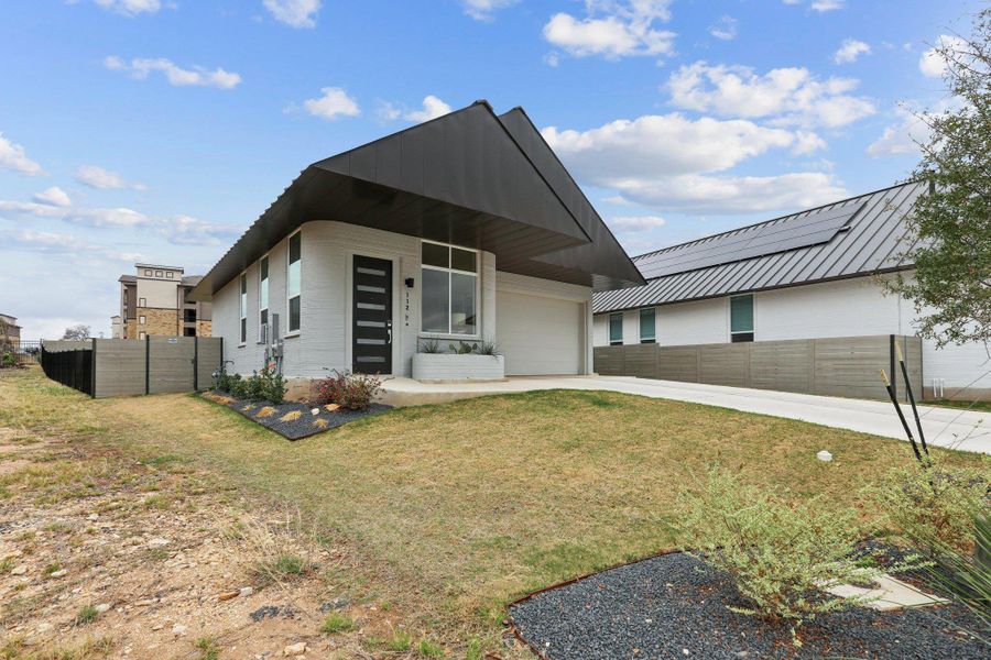 Contemporary house with driveway, an attached garage, a metal roof, and covered porch