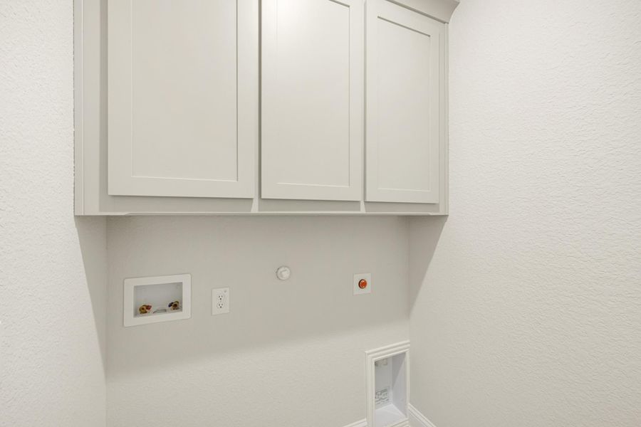 Laundry room with white upper cabinets, washer hookups, and dryer vent connection