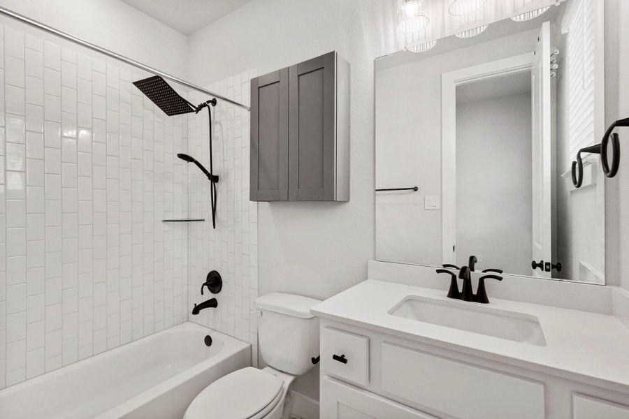 Bright bathroom with glossy subway tile surround, matte-black fixtures, and sleek vanity with large mirror.