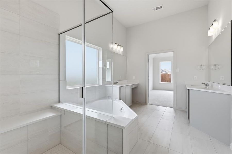 Full bathroom with two vanities, a bath, a stall shower, and light tile patterned floors