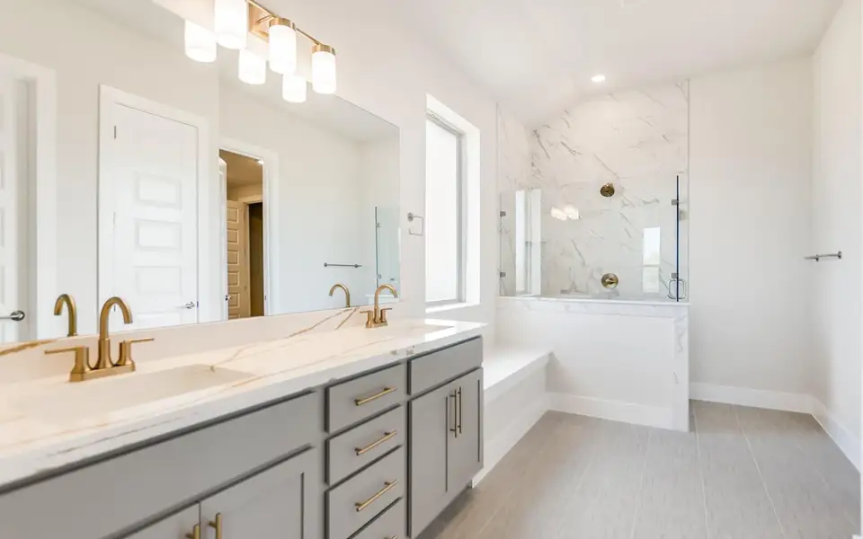 Bathroom with a marble finish shower, double vanity, and recessed lighting