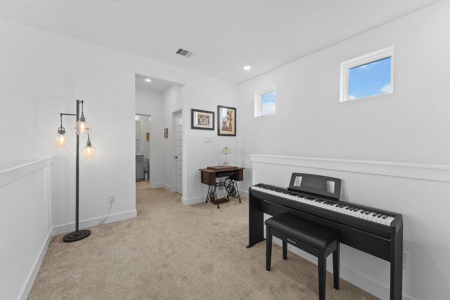 The spacious second-floor loft provides a flexible space for a music room or play area. The open-to-below design creates a bright and airy feel, connecting the second floor to the rest of the home.
