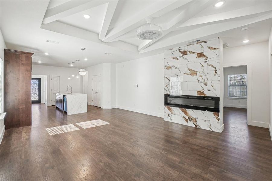 Unfurnished living room featuring beam ceiling, dark hardwood / wood-style flooring, and sink