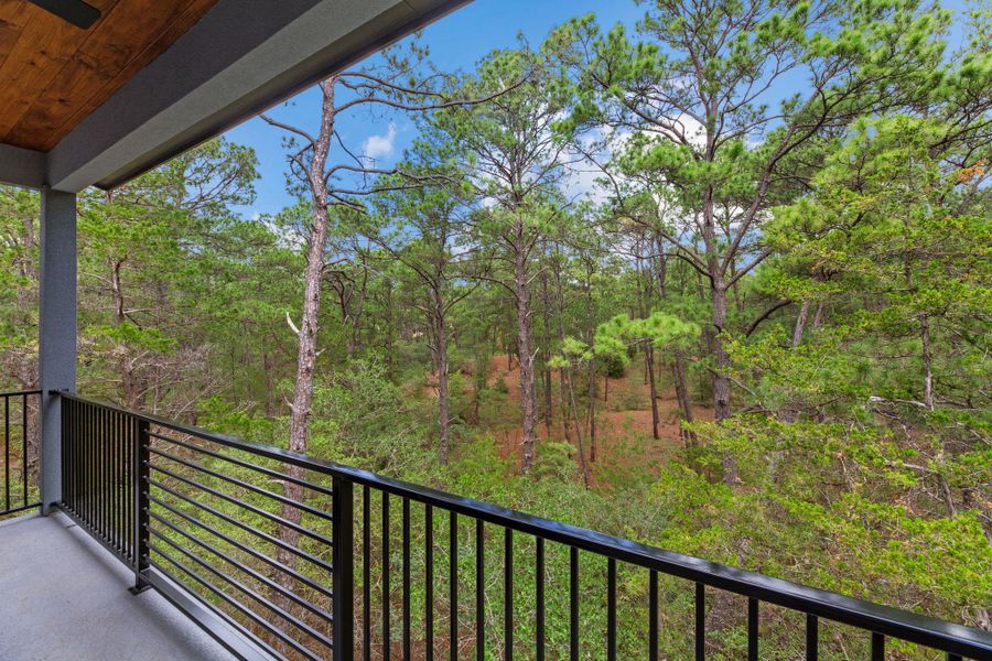 A private balcony extends into a dense, natural treeline, offering serene woodland views.