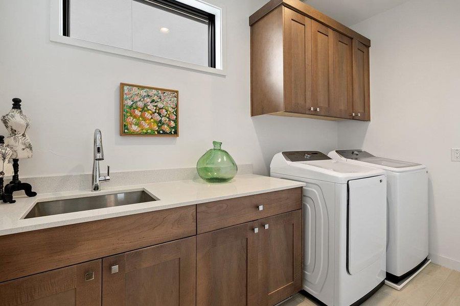 Utility room featuring wood-finish cabinetry, light-toned countertop, and an undermount sink with a gooseneck faucet