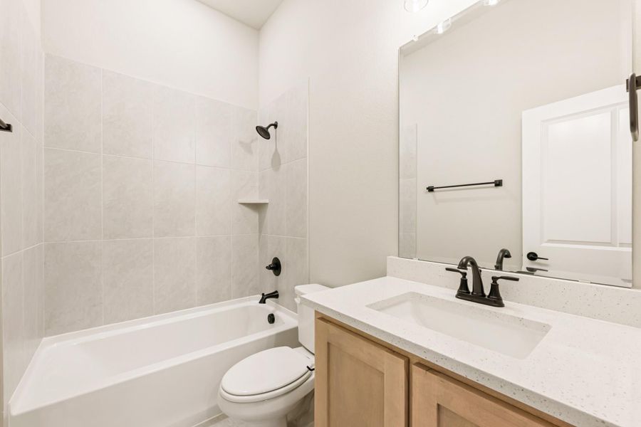Bathroom with tiled tub-shower combo, wood vanity with quartz countertop, and black fixtures Bathroom with tiled tub-shower combo, wood vanity with quartz countertop, and black fixtures