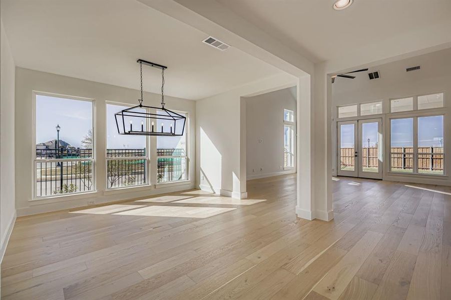 Unfurnished dining area featuring light wood finished floors, a chandelier, recessed lighting, and french doors Unfurnished dining area featuring light wood finished floors, a chandelier, recessed lighting, and french doors