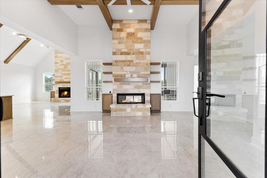 Open living area featuring soaring ceilings, stone fireplace, and seamless flow into the kitchen. Open living area featuring soaring ceilings, stone fireplace, and seamless flow into the kitchen.