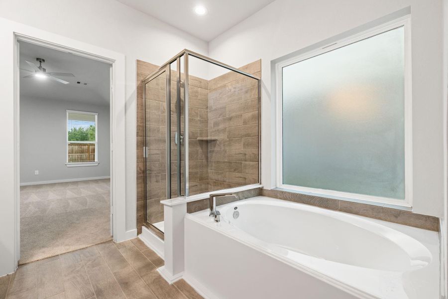 The primary en-suite has a soaking tub to give you that spa experience. The large privacy window allow lots of nature light in the space. Sample photo of completed home with similar floor plan. As-built interior colors and selections may vary.