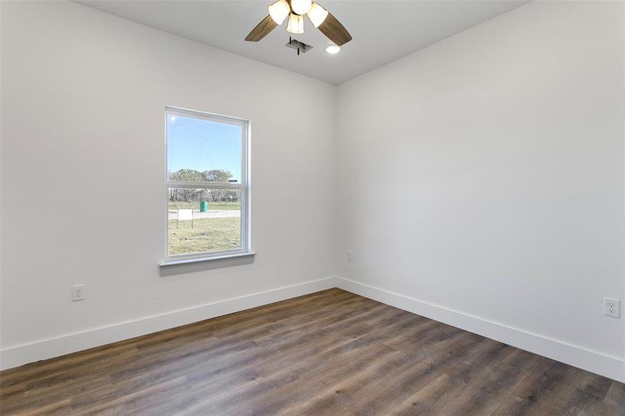 Empty room featuring ceiling fan and dark wood-type flooring