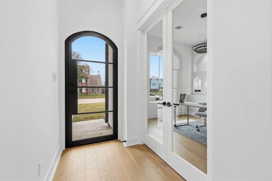 From the moment you enter, the metal front door sets a sophisticated tone, leading seamlessly to a light-filled office framed by classic dual doors.