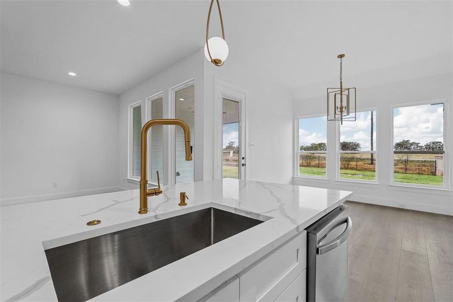 Kitchen with healthy amount of natural light, light wood-style floors, decorative light fixtures, white cabinets, and recessed lighting Kitchen with healthy amount of natural light, light wood-style floors, decorative light fixtures, white cabinets, and recessed lighting