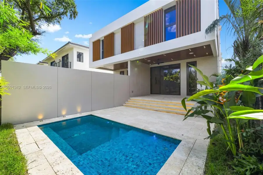 Modern two-story exterior with vertical wood-slat accents, featuring a stone-paved patio, an inground pool, tiered concrete steps, and integrated perimeter lighting Modern two-story exterior with vertical wood-slat accents, featuring a stone-paved patio, an inground pool, tiered concrete steps, and integrated perimeter lighting