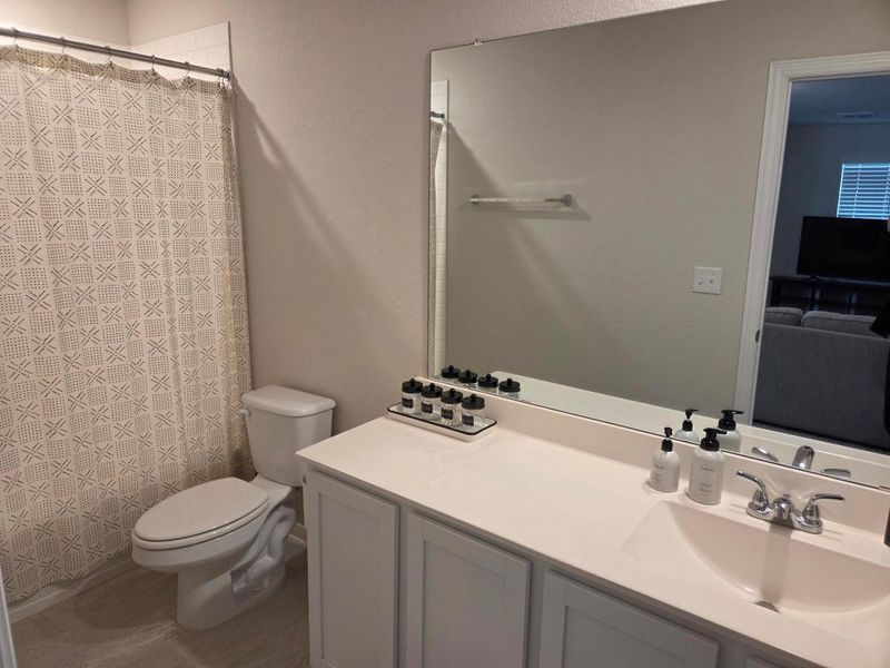 Bathroom featuring a white vanity with an integrated sink, polished chrome faucet, and a large wall-mounted mirror