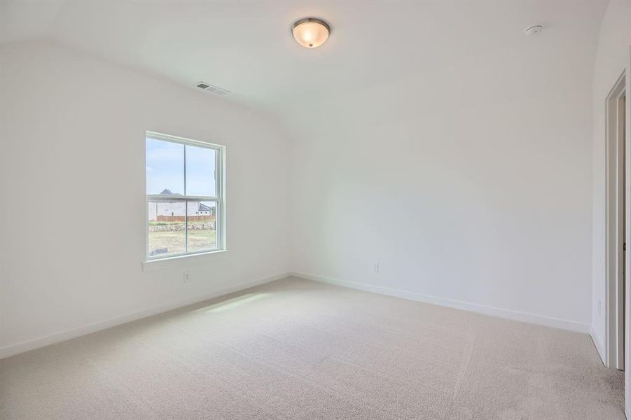 Empty room featuring light carpet, vaulted ceiling, baseboards, and a smoke detector