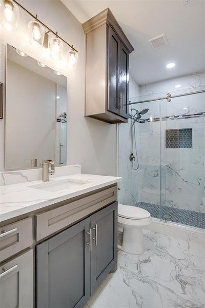 Bathroom with a shower with door, vanity, and toilet