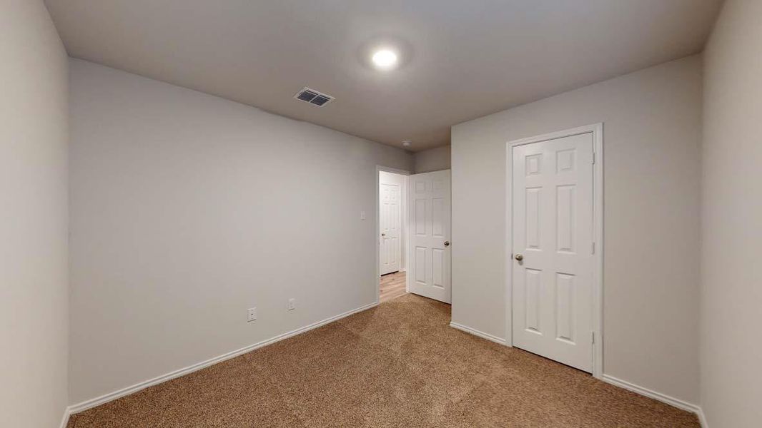 Carpeted room with light gray walls, white trim, and a six-panel interior door