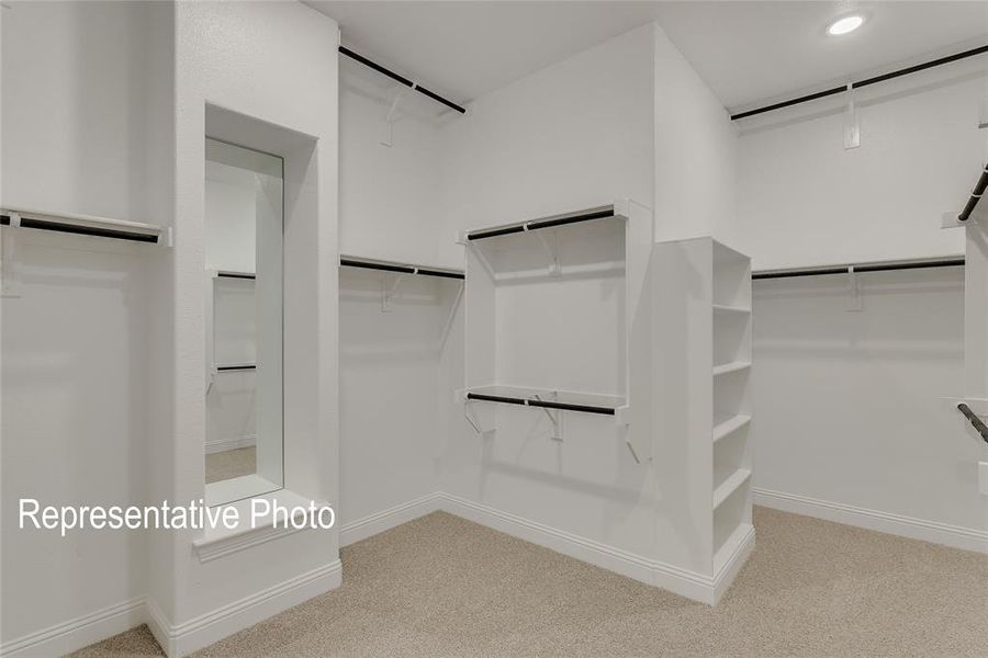 Spacious walk-in closet featuring built-in shelving, multiple hanging rods, recessed lighting, and a full-length mirror