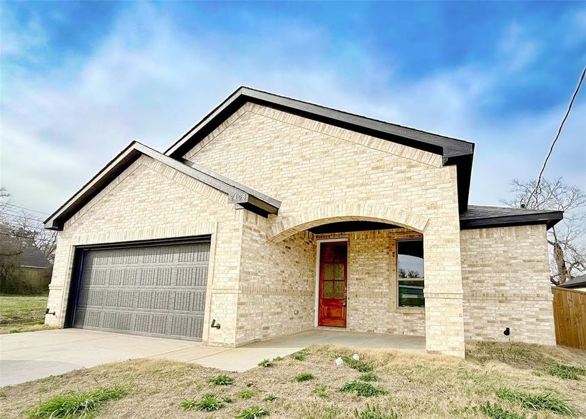 View of front of home with a garage, brick siding, and driveway