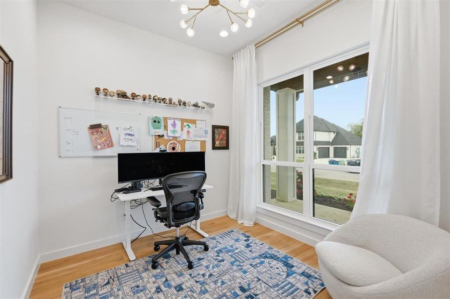 Office area featuring light wood-style floors and a chandelier