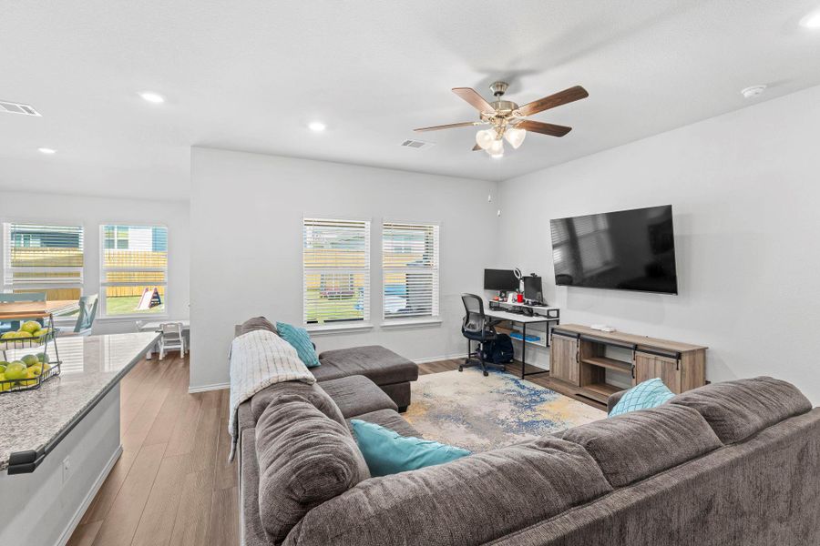 An inviting great room with wood flooring extends to a well-lit dining area, offering a relaxed and open living experience. An inviting great room with wood flooring extends to a well-lit dining area, offering a relaxed and open living experience.