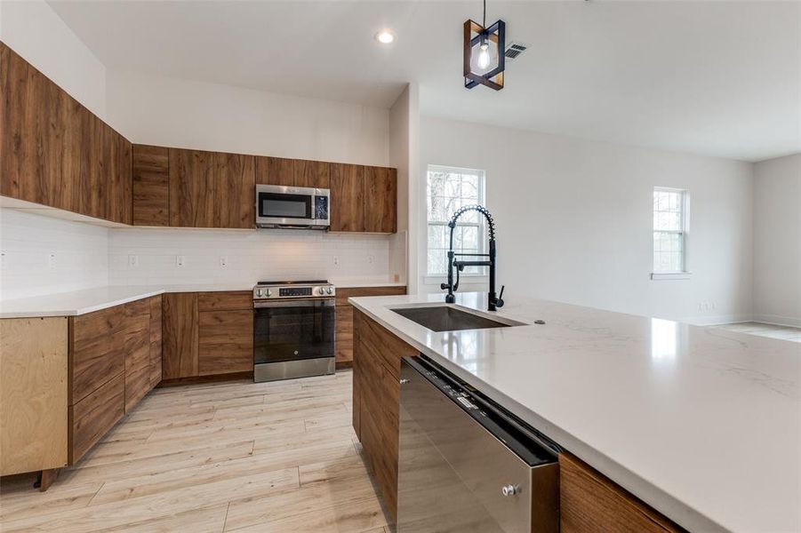 Kitchen with visible vents, modern cabinets, a sink, appliances with stainless steel finishes, and decorative backsplash