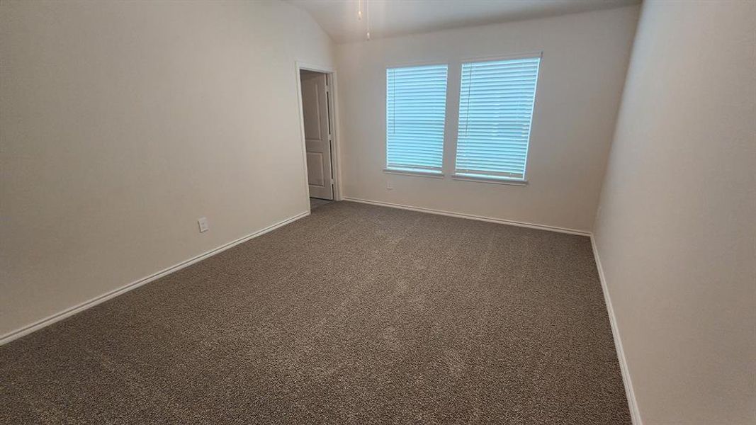 Spacious room featuring neutral carpeting, light-toned walls, and a vaulted ceiling Spacious room featuring neutral carpeting, light-toned walls, and a vaulted ceiling