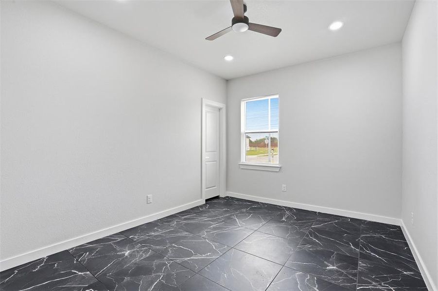 Room featuring black tiled flooring with white veining, white walls, and white baseboards