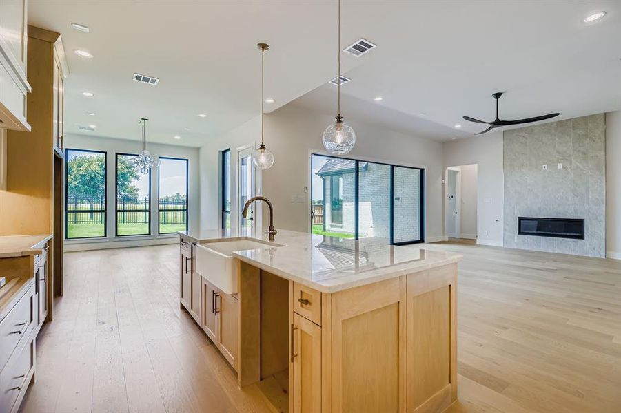 Kitchen featuring light wood finished floors, a ceiling fan, light brown cabinetry, recessed lighting, and open floor plan