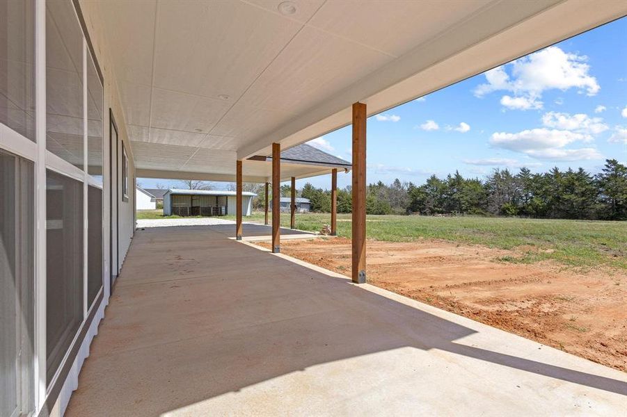 The property features an extensive covered patio with a concrete surface and substantial wooden support pillars