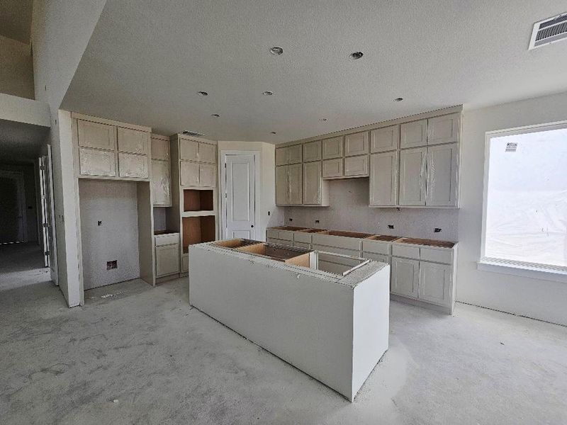 Kitchen with a center island and unfinished concrete flooring Kitchen with a center island and unfinished concrete flooring