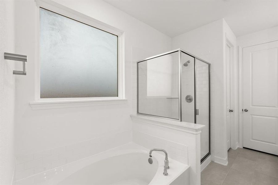 This additional view of your primary bathroom features tile flooring, fresh paint, walk-in shower, a separate garden tub, and a large walk-in closet.