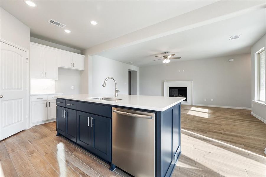 Kitchen with dishwasher, a kitchen island with sink, white cabinets, light wood-style floors, and recessed lighting