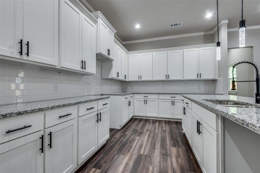 Kitchen with white cabinetry, hanging light fixtures, decorative backsplash, and recessed lighting Kitchen with white cabinetry, hanging light fixtures, decorative backsplash, and recessed lighting