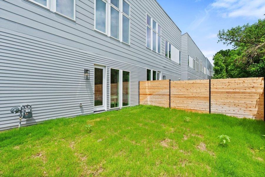 The property features a private grassy yard with a wooden fence