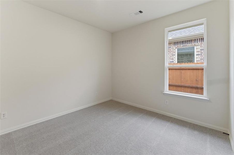 Spacious room featuring neutral carpeting, light-colored walls, white baseboards, and a single window with white trim