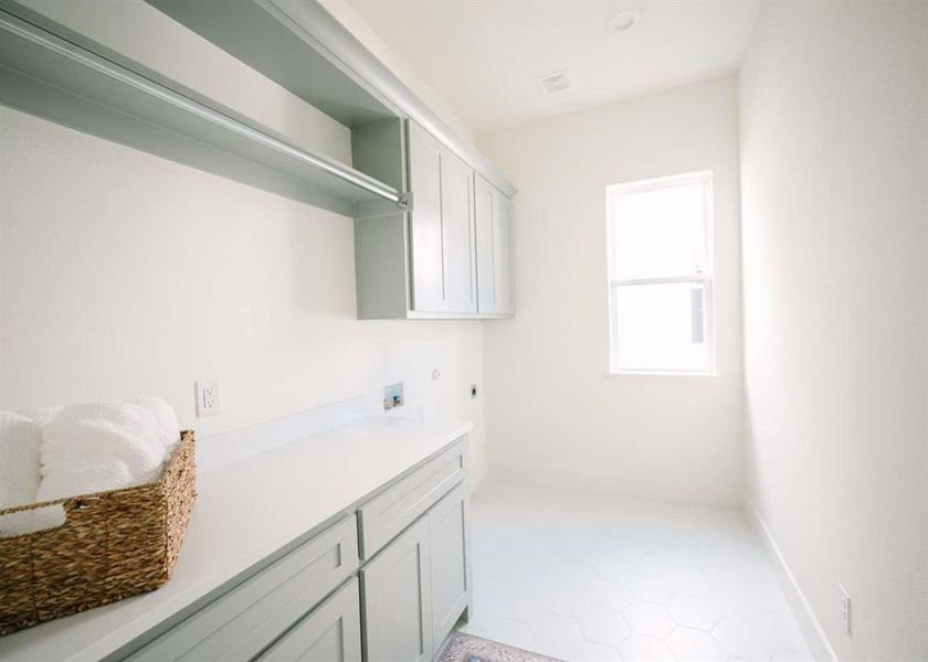 Washroom featuring hookup for a washing machine, hookup for an electric dryer, light tile flooring, and cabinets