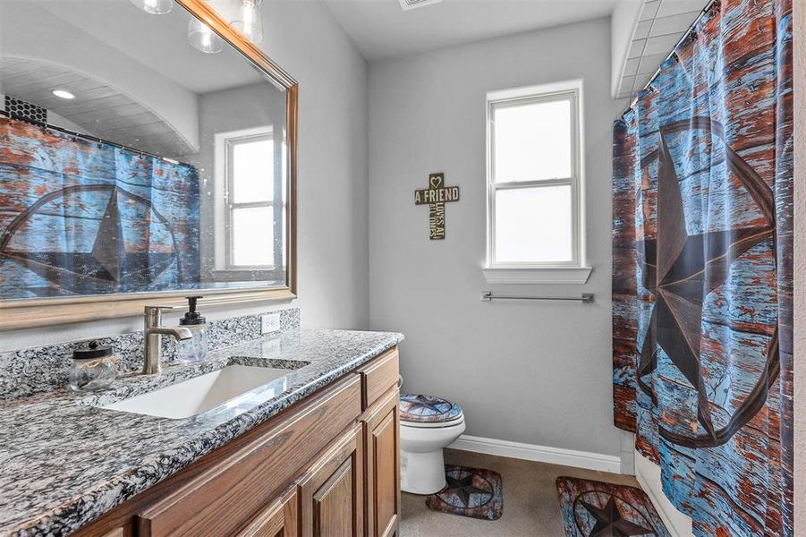 Bathroom featuring toilet, vanity, and a shower with shower curtain