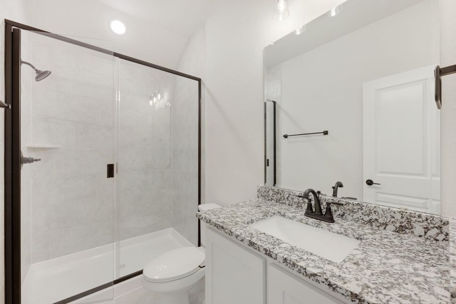 Bathroom with granite countertop vanity, glass-enclosed tile shower, and dark bronze fixtures