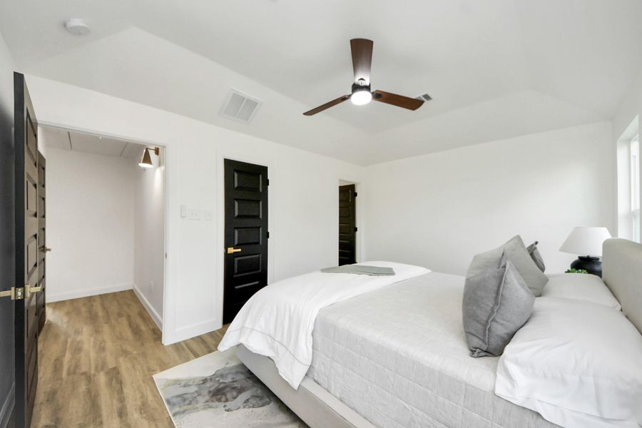 A serene, sunlit bedroom with vaulted ceilings that create an airy, restful retreat. Large windows invite in natural light, while neutral tones, a cozy bed, and simple, stylish touches complete the calm and inviting atmosphere.