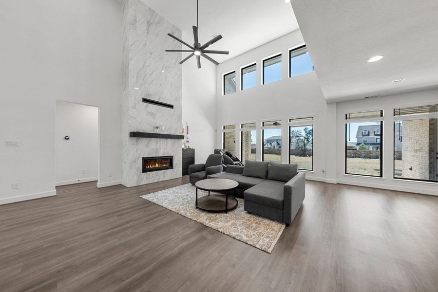 Living area featuring ceiling fan, a premium fireplace, wood finished floors, and baseboards